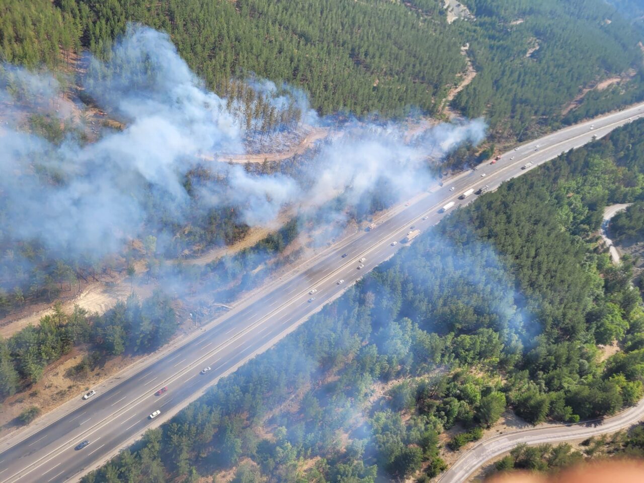 Adana'nın Pozantı ilçesinde otoyoldaki otomobilde çıkıp ormanlık alana sıçrayan yangına